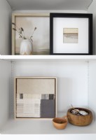 Display of framed artwork on white shelving unit - detail