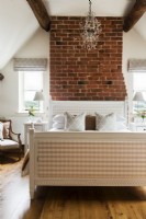 Chandelier and exposed brickwork in modern country bedroom
