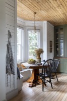 Built-in window seat around dining table in country dining room