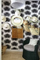 A tropical hat room with black and white palmetto wall paper and vintage wicker furnishings.