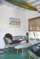 A screen porch with vintage furnishing and beach, surfing motifs