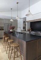Row of wooden bar stools next to large island in modern kitchen