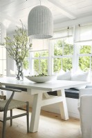 Modern dining room in white with window seat and wishbone chair