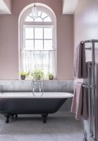 Pink Pastel bathroom with roll top bath and chrome towel rail
