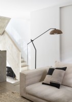 Floor lamp over cream sofa with concrete staircase in background