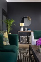 Green velvet sofa, graphic rug and black walls in living room