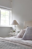 Detail of white scandi bedroom with pastel cushions