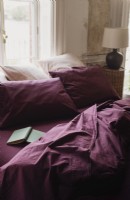 Plum French bed linen on unmade bed