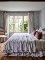 Neutral bedroom with armchair and wooden floorboards