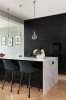 Contemporary kitchen with tall black wall cupboards and marble island.