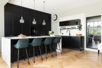 Contemporary large kitchen with tall black wall cupboards and island.