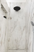 Contemporary marble wet room with large shower head.