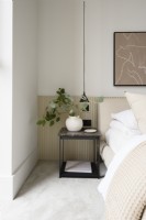 Bedside table with vase and leaves in a neutral bedroom