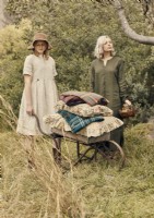 Two women in garden with cushions on antique wheelbarrow