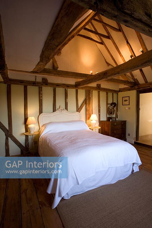 Boonshill Farm, East Sussex. Interior of bedroom with wooden floorboards and exposed beams 
