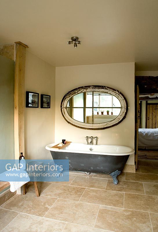 Boonshill Farm, East Sussex. Interior of bathroom with roll top bath, wooden bench from india  and mirror made from old window.