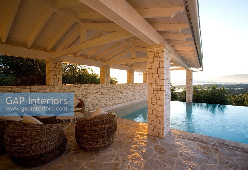 Corfu, Greece: Villa in north east Corfu. Rectangular infinity swimming pool at dawn with wicker seats 