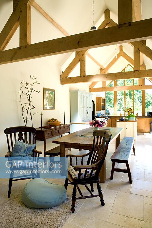 Open plan dining room and kitchen with dining table wooden beams and limestone floor