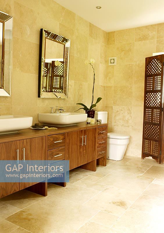 Classic bathroom with twin basins and dark wood cupboards  Large sandstone tiles and wooden screen