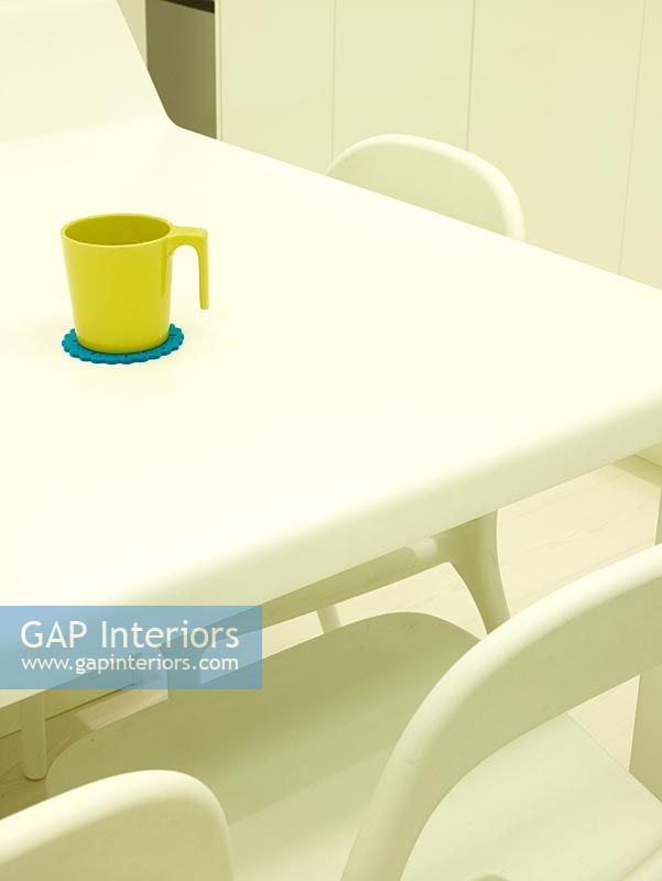 Detail of white dining table with green mug