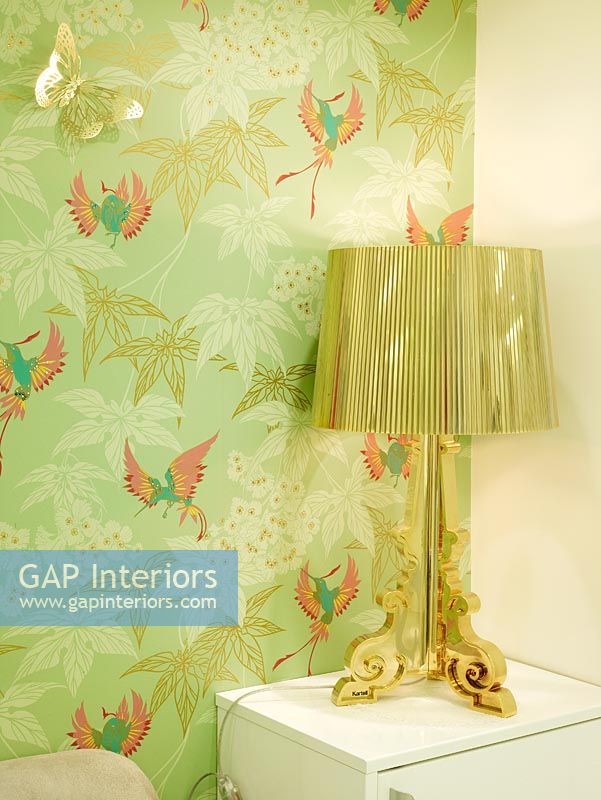 Detail of gold lamp and green patterned wallpaper