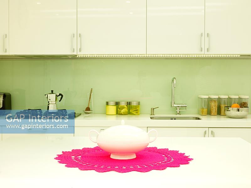 Modern kitchen with teapot on pink table mat