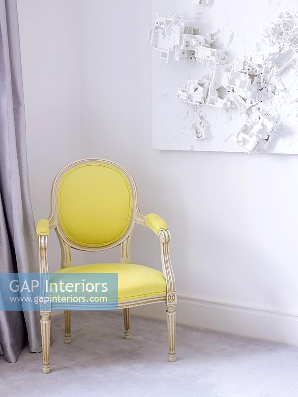 Living room with classic upholstered yellow chair and abstract art on the wall