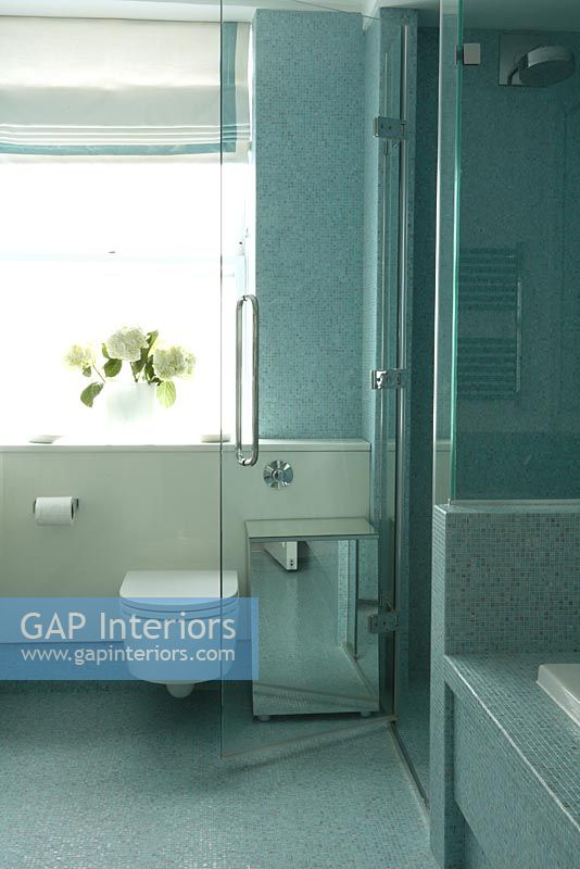 Modern bathroom with separate shower cubicle and bath and blue mosaic tiled walls and floor