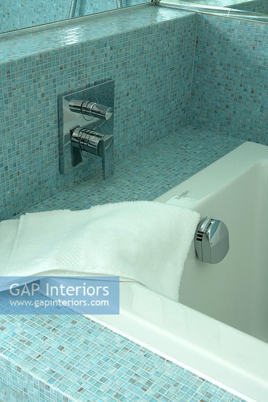 Modern bath with blue mosaic tiles and towel draped over the side