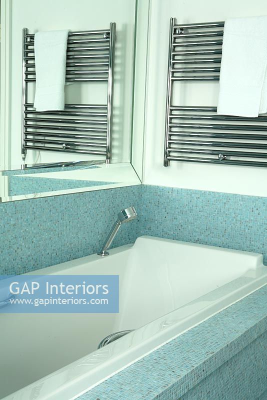 Modern bath with blue mosaic tiles and towel hanging on towel radiator