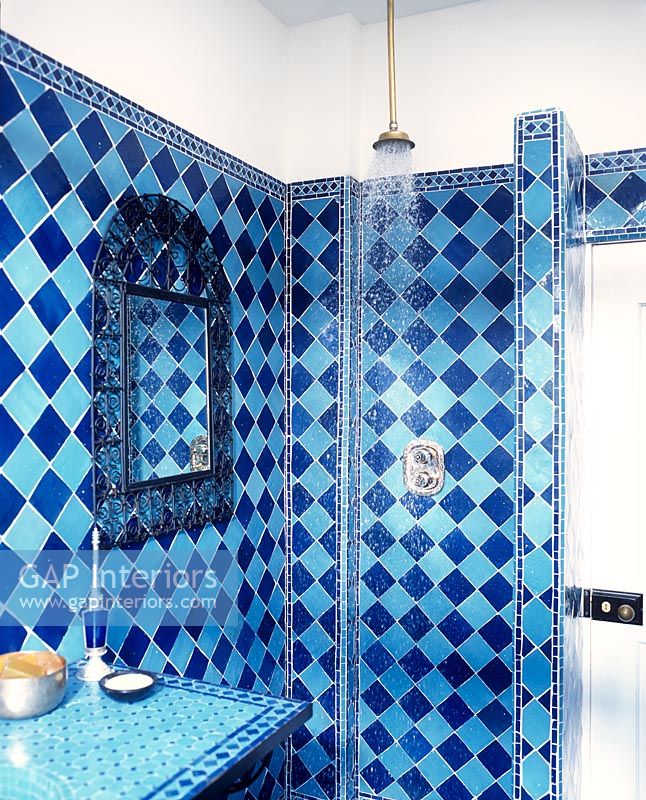 Quirky bathroom with blue tiled walls and open shower 