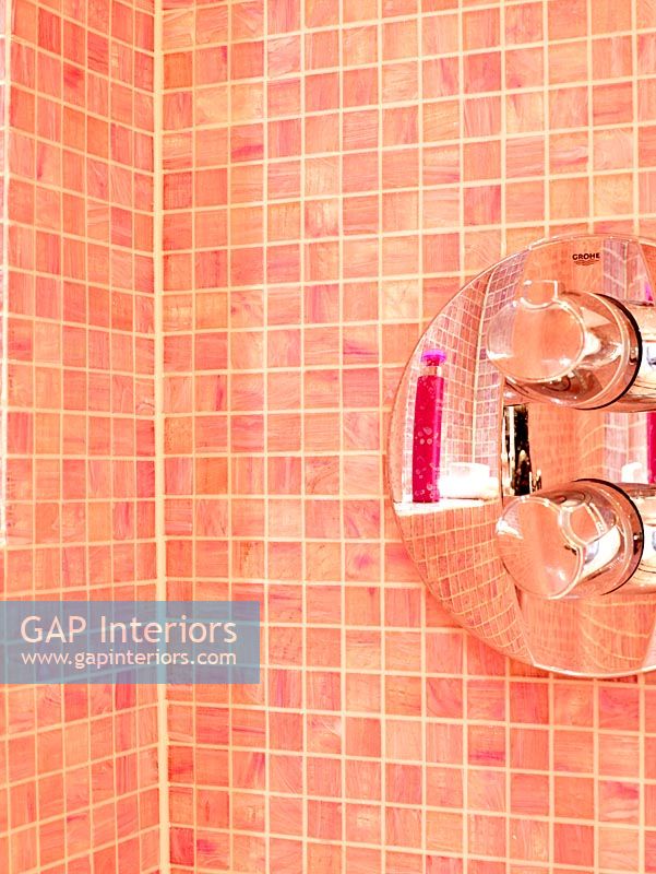 Detail of shower fitting on pink mosaic tiled walls