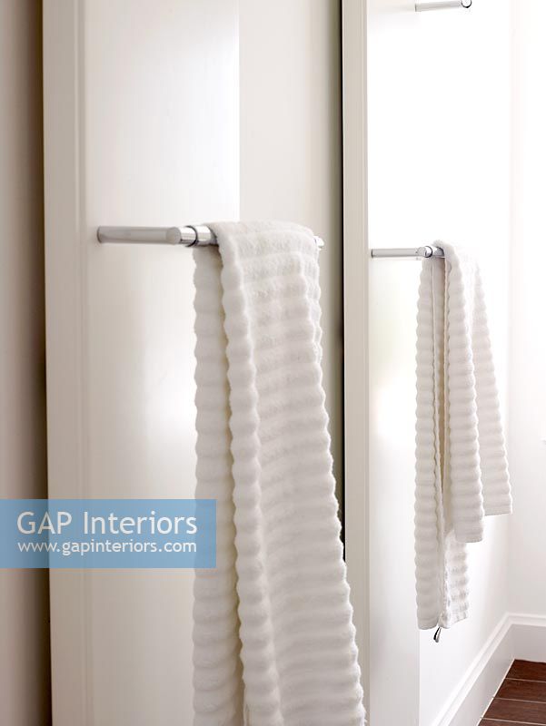 Towels hanging on radiators in modern white bathroom