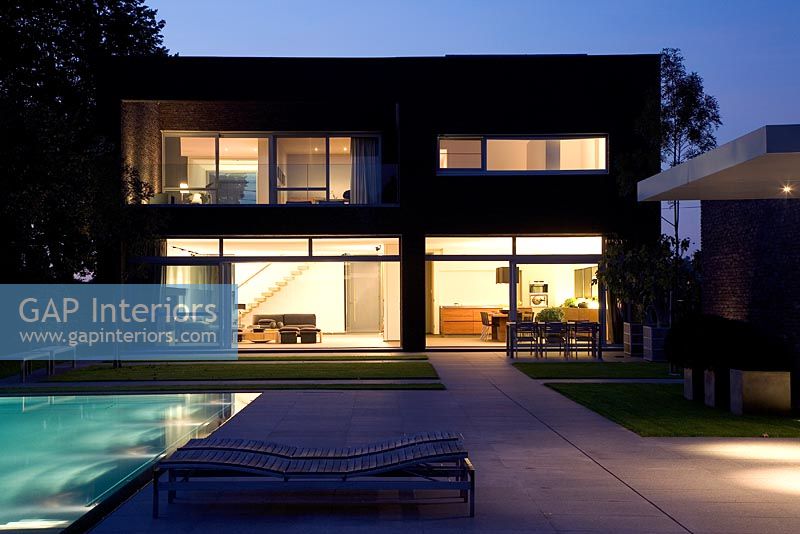 Modern house exterior at night with pool 