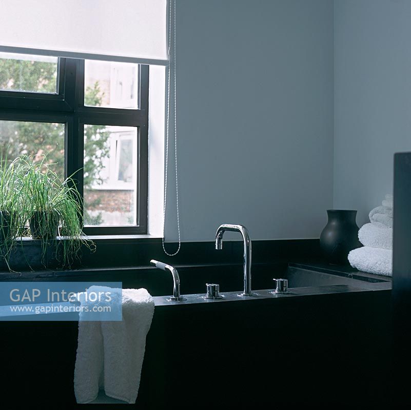 Modern bath in bathroom with pot plants on window sill