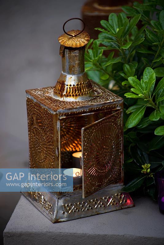 Moroccan lantern with lit candle in garden