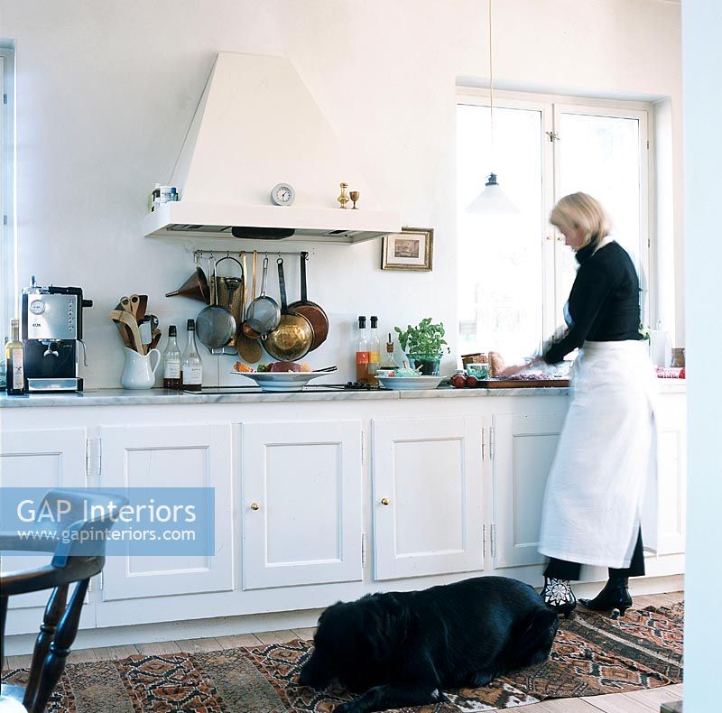 Woman fixing food in the kitchen with her pet dog