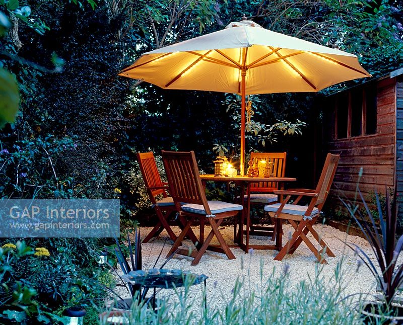 Table and chairs in garden with illuminated umbrella