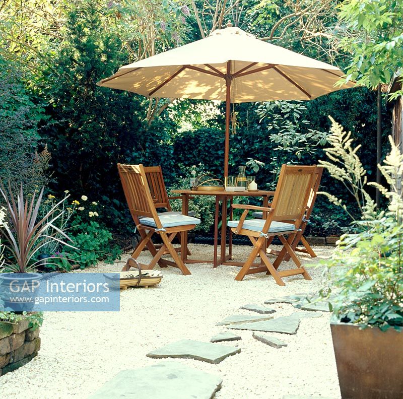 Table and chairs in small garden with umbrella