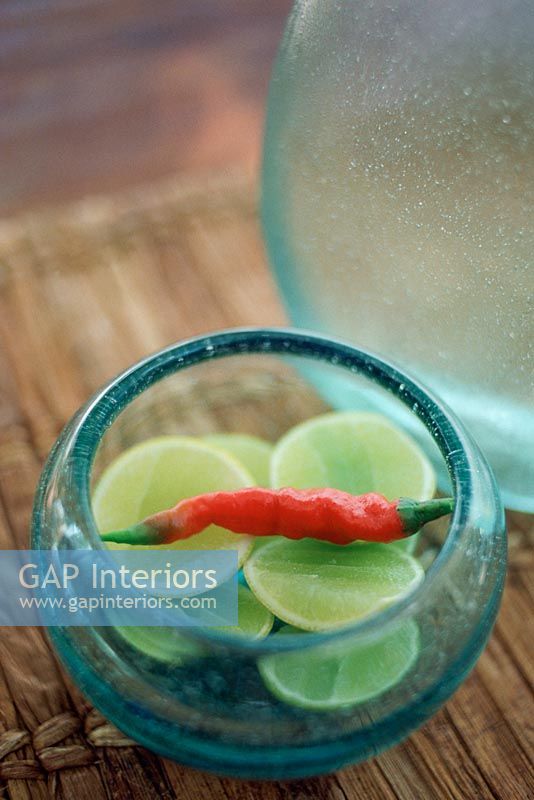 Glass bowl with sliced lime and a red chili