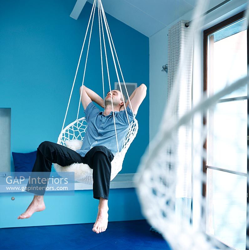 Man sitting in a hanging chair relaxing