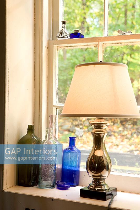 Lamp and glass bottles on windowsill 