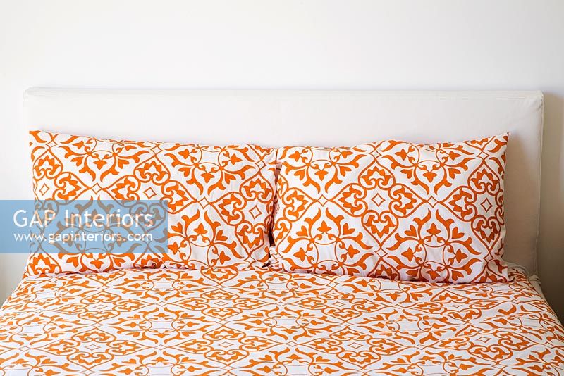 Bed with Orange Print Sheets and Pillows