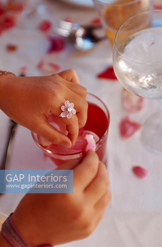 Woman's hand arranging petals in glass, close-up