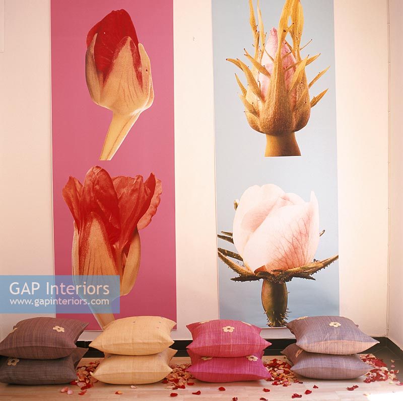 Pillows stacked on the floor in front of photos of flowers