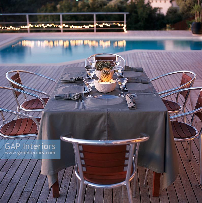 Place setting on dining table with swimming pool in background