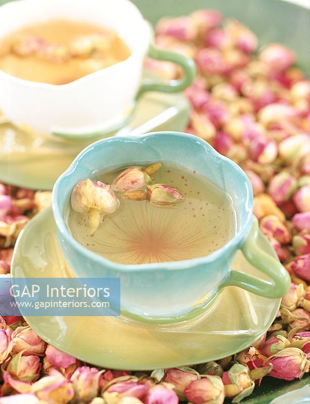 Rose tea in cup with flower petals beside