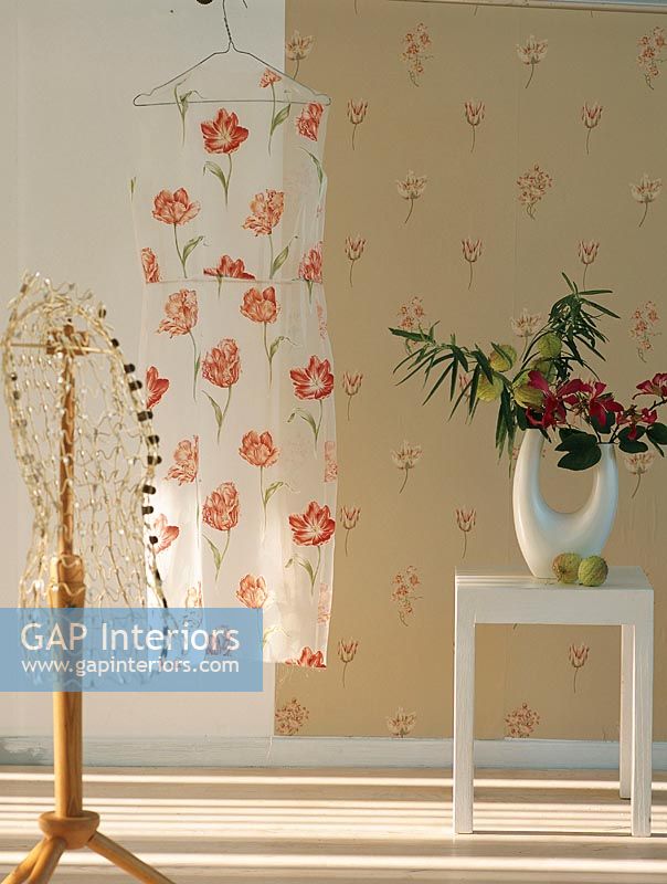 Floral print dress hanging in front of floral pattern wallpaper