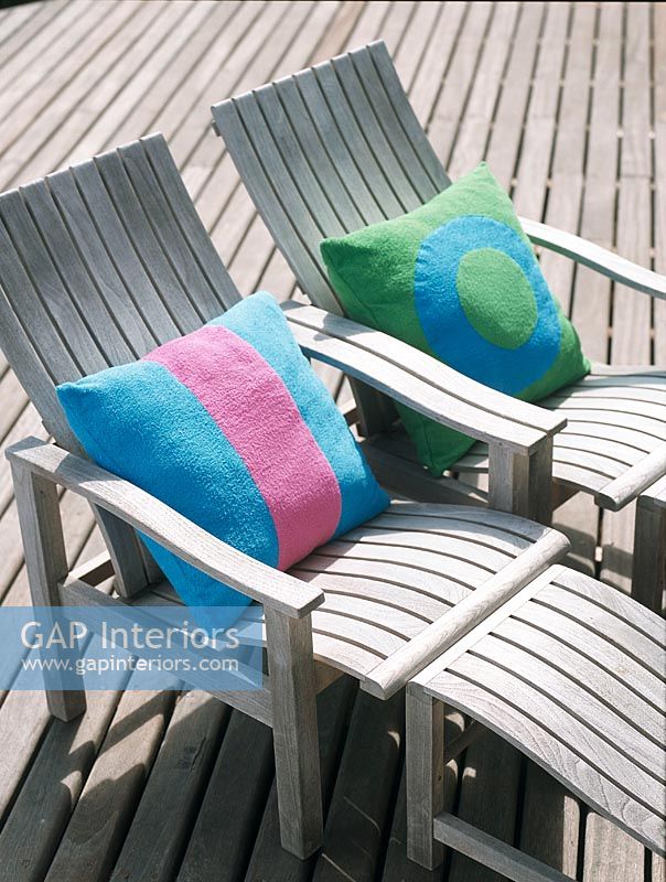 Two wooden beach chairs with colourful pillows