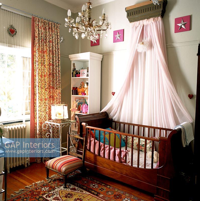 Childs wooden crib with pink canopy curtain